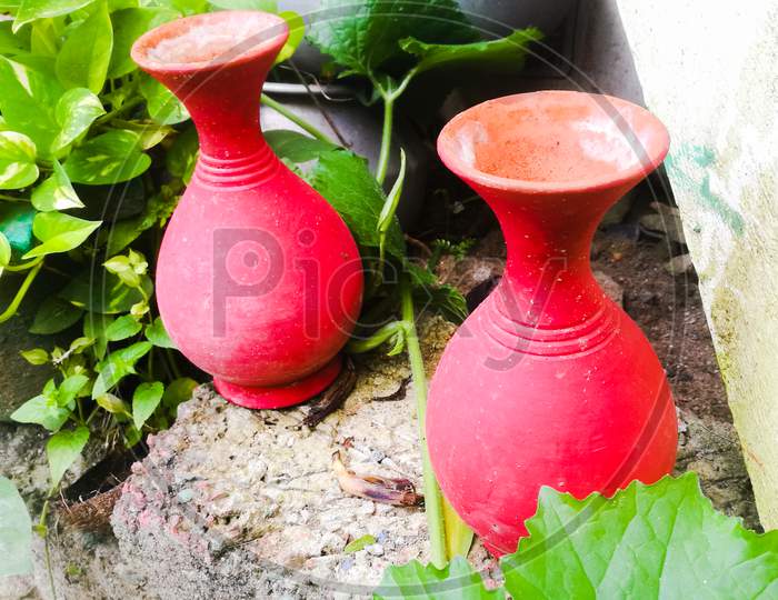 Two Earthen Pots Of Red Color Placed Side By Side In A Garden.