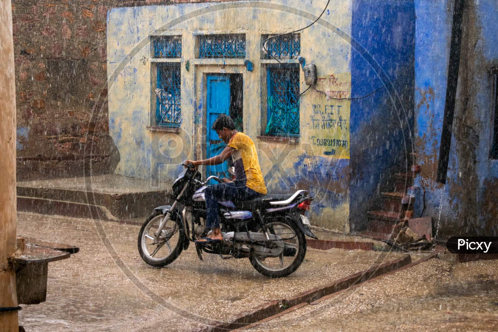 People ride bike while it rains heavily during monsoon season in Bharatpur
