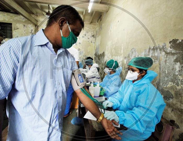 A healthcare worker checks BP of a recovered Covid-19 patient during screening for plasma donation, at a camp set inside a classroom of a school, at Dharavi, in Mumbai, India on July 23, 2020.