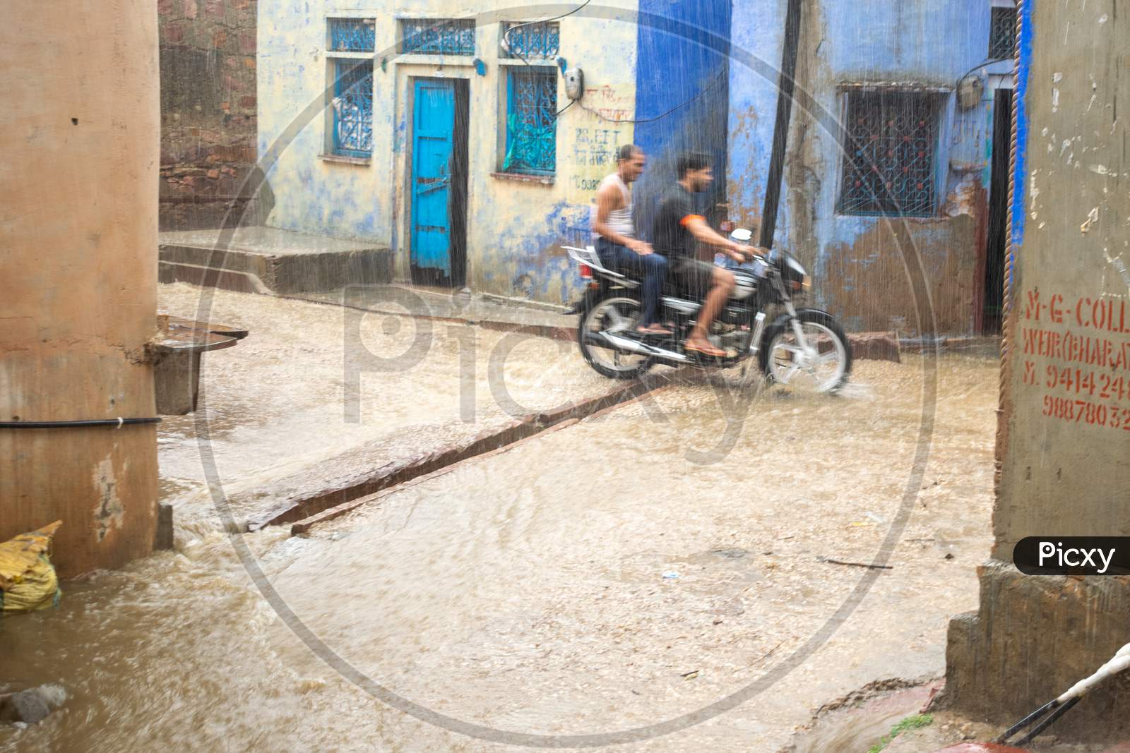People ride bike while it rains heavily during monsoon season in Bharatpur