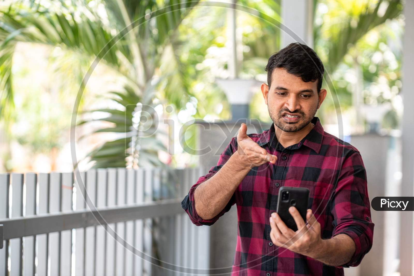 Portrait of a Young Indian Man makes gestures while talking on a video call.