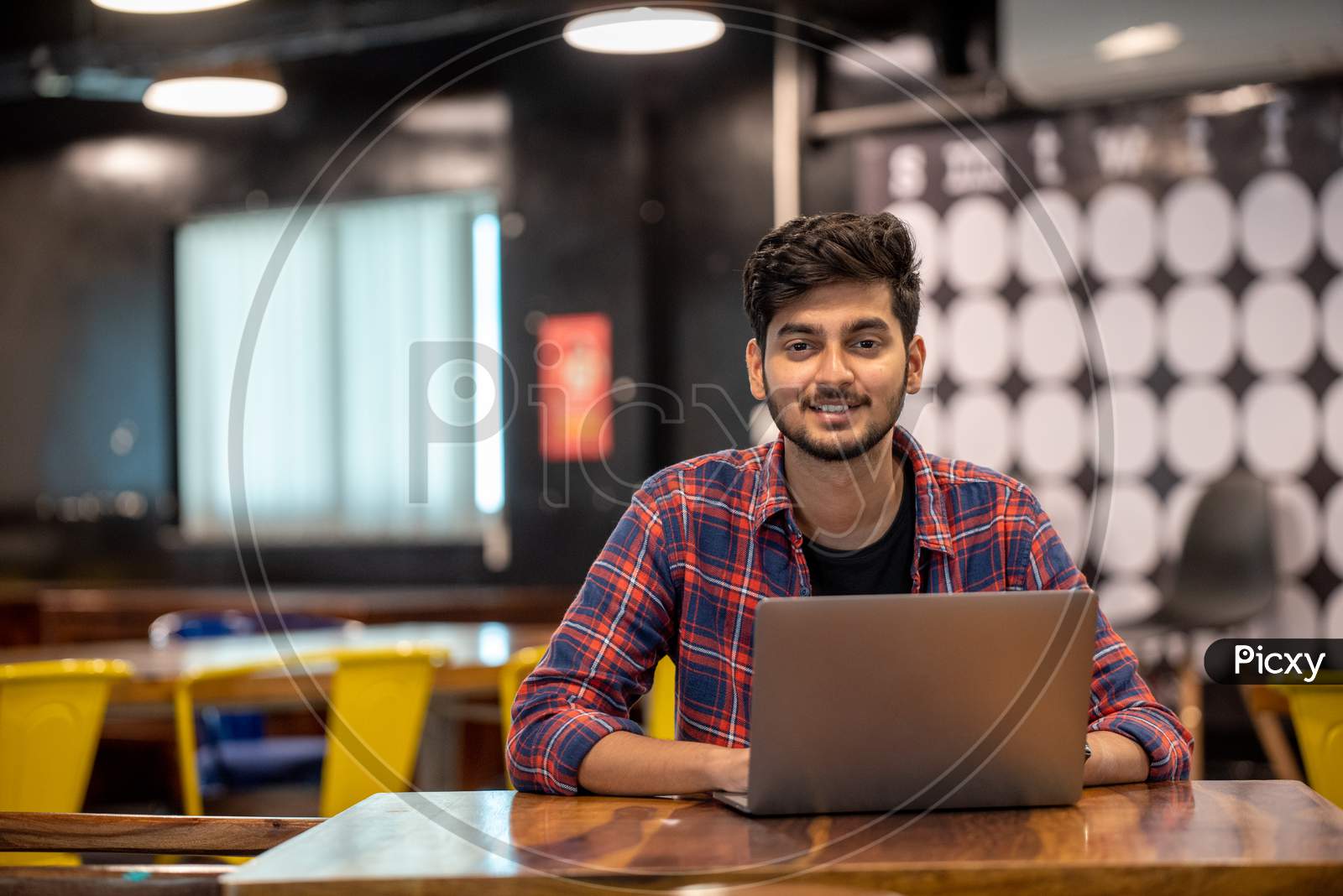Smiling Young Indian Man working on a Laptop in an office