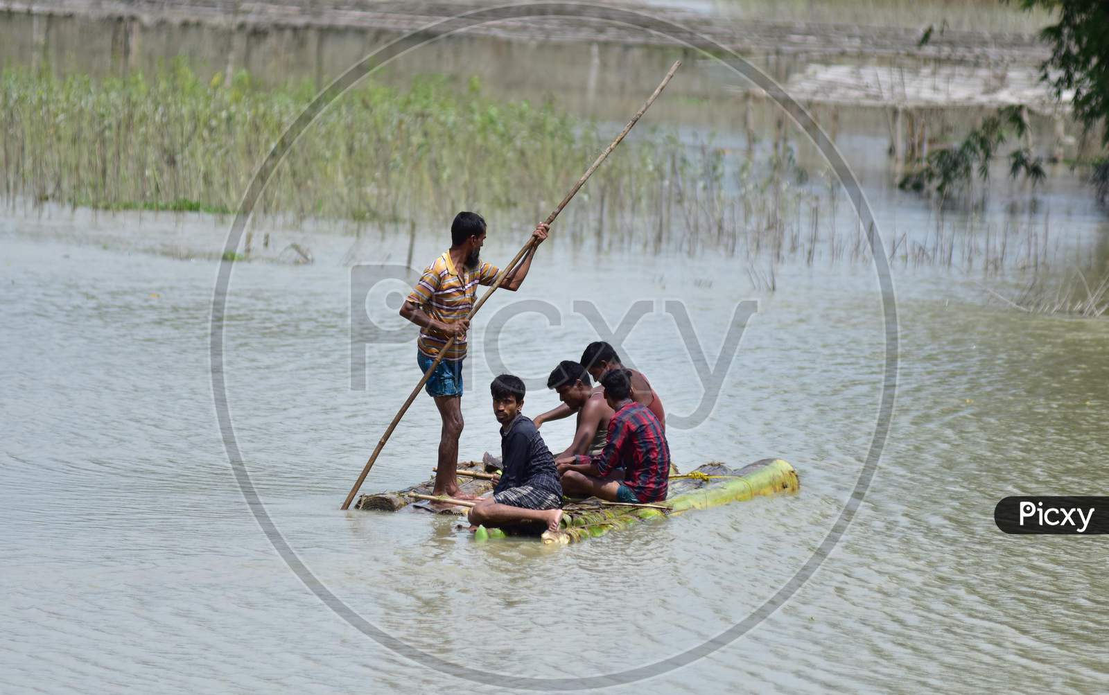 Villagers Row A Makeshift Raft Through A Flooded Field  At The Flood-Affected Laokhowa Wildlife Sanctuary In Nagaon District Of Assam On July 25, 2020.