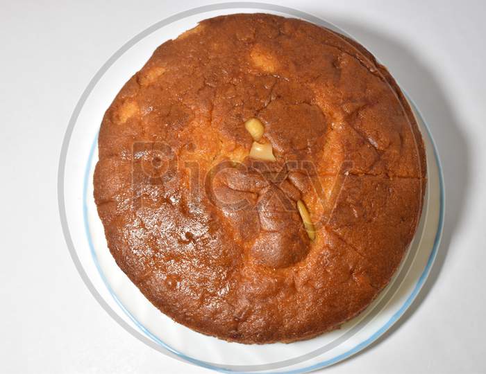 Freshly round baked Sponge Vanilla cake with Kaaju (Cashew) mix isolated on the white background. Delicious chocolate cake on table close-up Side View.