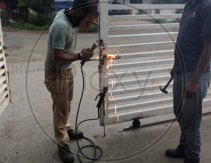 Worker Welding On Iron In Industrial Workshop