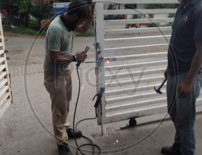 Worker Welding On Iron In Industrial Workshop
