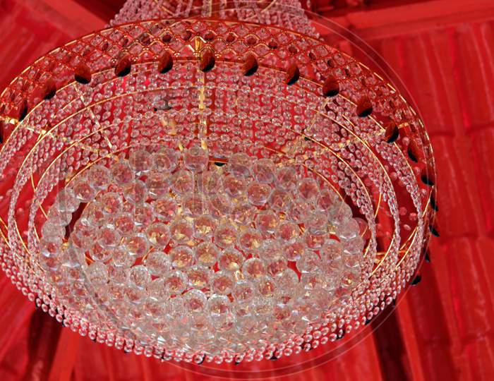 Beautiful Chandelier made by glass hanging under red shade on daylight for decoration.