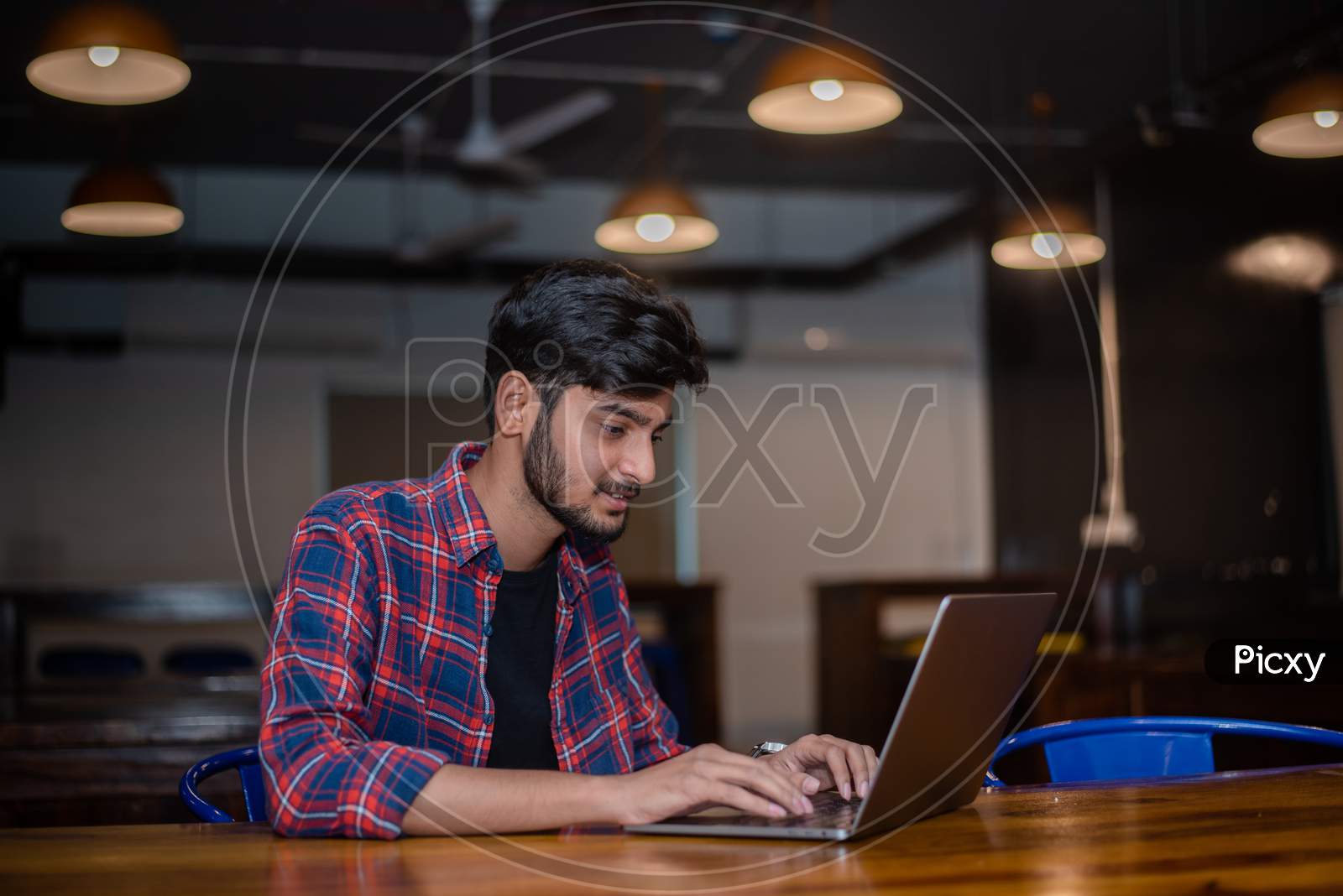 Young Indian man working on a laptop in a cafe