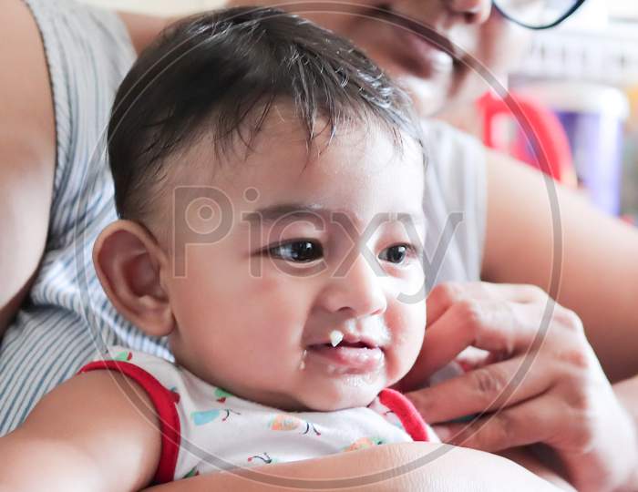 An Infant Toddler Baby Boy Smiling While Feeding Solid Food