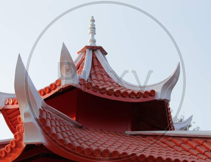 Red White colored Buddhist Temple shaped partial and cropped structure with sky.