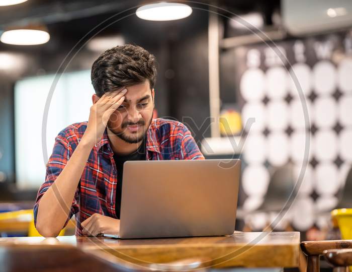 Frustrated Young Indian Man while working on a laptop