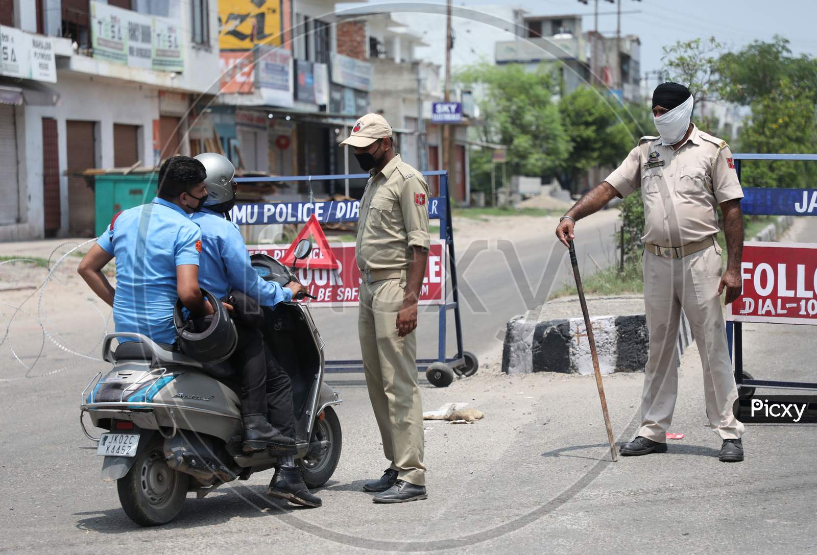 Paramilitary soldiers inspect passersby outside a containment area as authorities imposed weekend lockdown from 6 pm Friday to 6 am Monday, in Jammu on July 22, 2020.