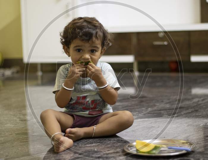 A Little Child Eating Mango Fruits , Indoors Boys