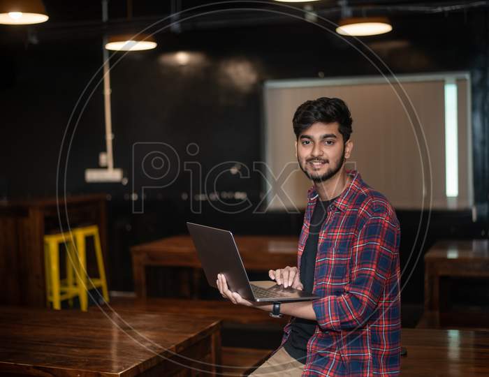 Smiling Young Indian Man working on a Laptop in an office