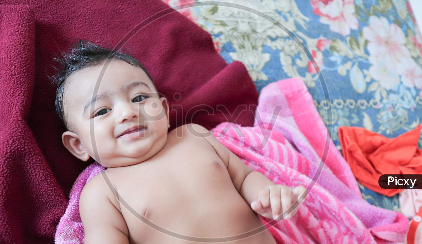 An Infant Toddler Baby Boy Smiling On A Magenta Towel