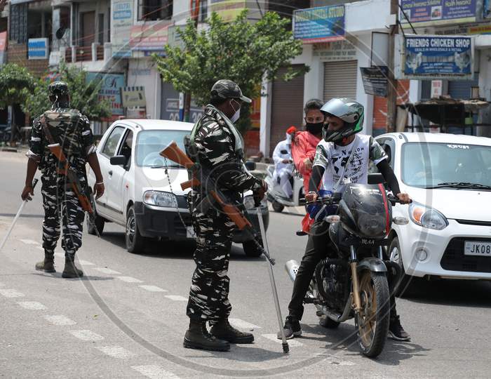 Paramilitary soldiers inspect passersby outside a containment area as authorities imposed weekend lockdown from 6 pm Friday to 6 am Monday, in Jammu on July 22, 2020.