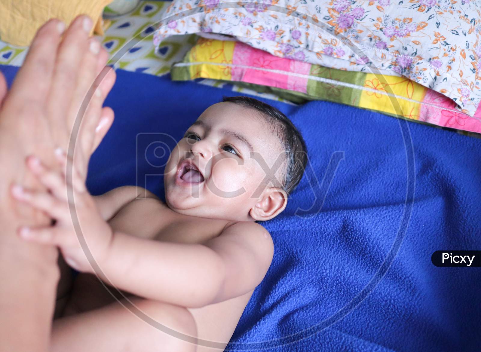 An Infant Toddler Baby Boy Smiling On A Blue Towel