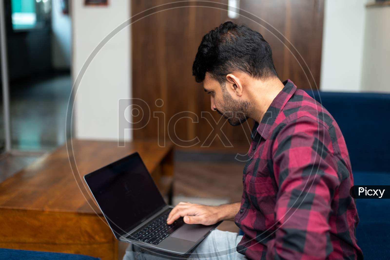 Young Indian man working on a laptop in office.
