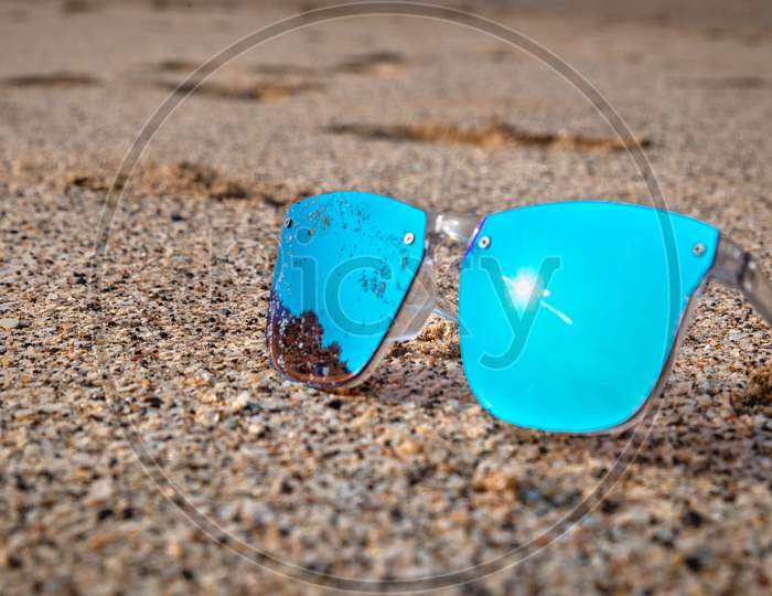 Image of Blue sunglass on beach sand Beach-SN489221-Picxy