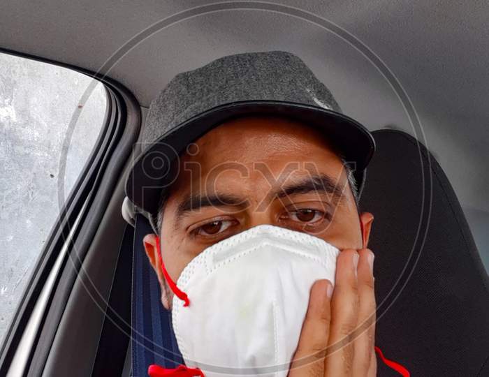 New Delhi India – July 3 2020 : Man in protective mask sitting inside his car amid safety from Coronavirus Covid 19, Mature Man in medical mask for pandemic COVID 19 protection