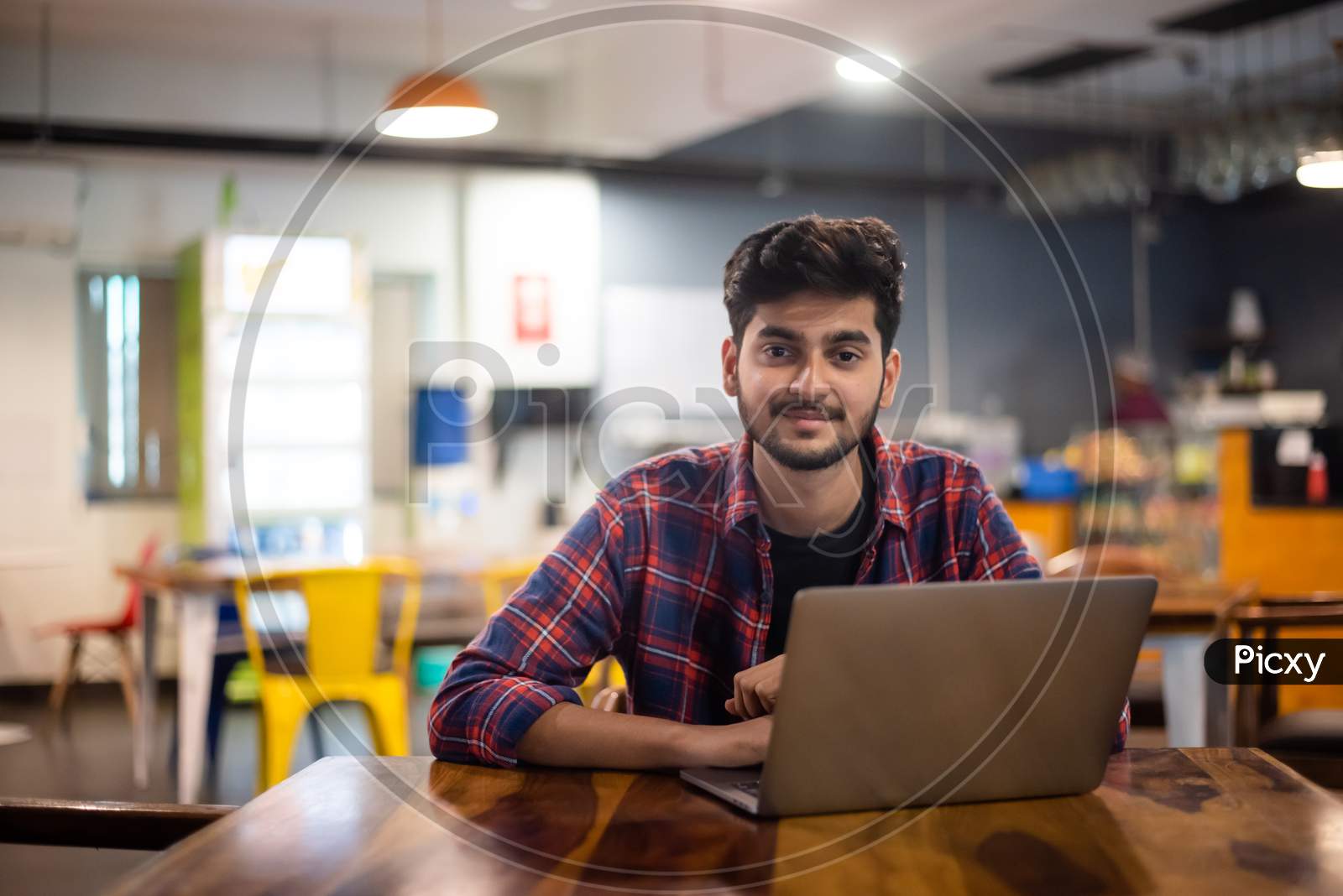Smiling young Indian man working on a laptop in office