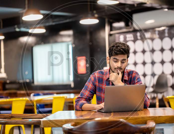 Young Indian professional Man working on a laptop in office.