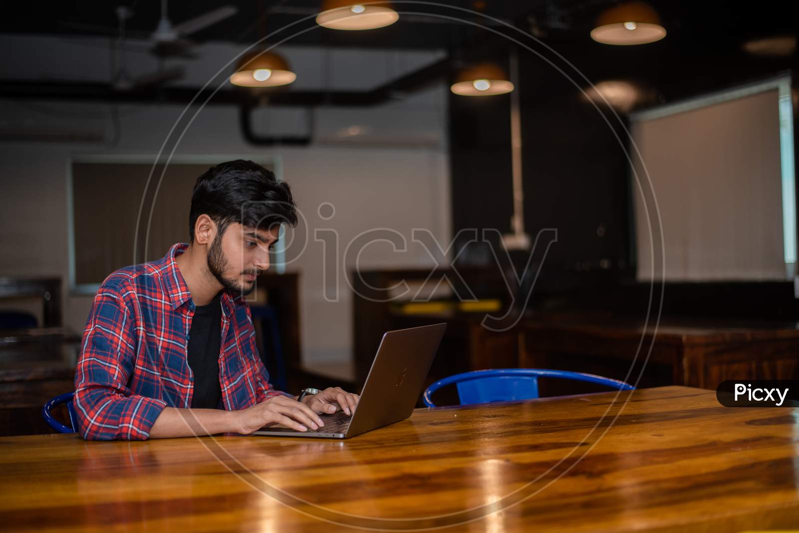 Young Indian man working on a laptop in a cafe