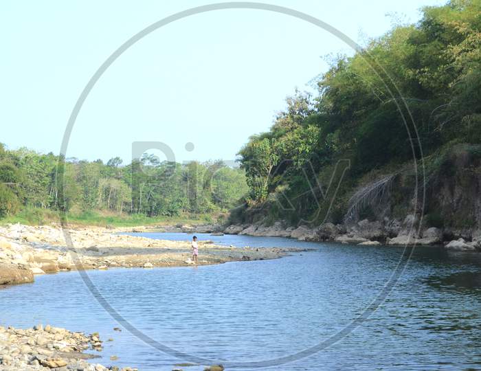 River During The Dry Season With Looks Far Away Fishing Child