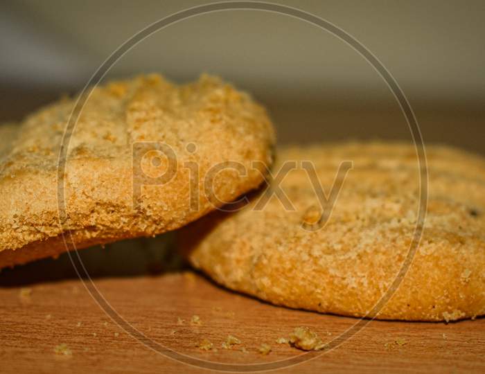 A Stack Of Delicious Wheat Round Biscuits With A Few Crumbs Isolated On Brown Table