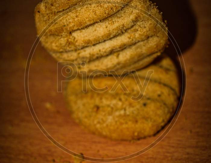 A Stack Of Delicious Wheat Round Biscuits With A Few Crumbs Isolated On Brown Table