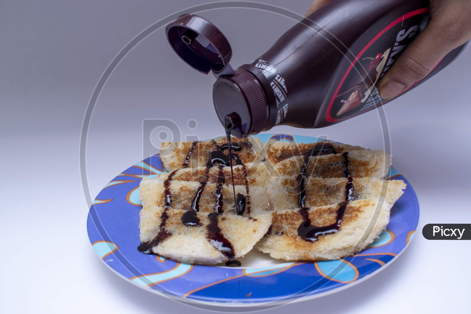 Pouring And Garnishing Hot Choco Lava Bread With Chocolate Syrup Or Sauce In Brown Bottle