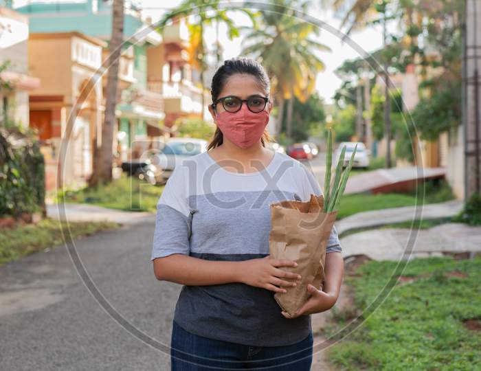 Young Indian woman with grocery bag bought from local vendors near home