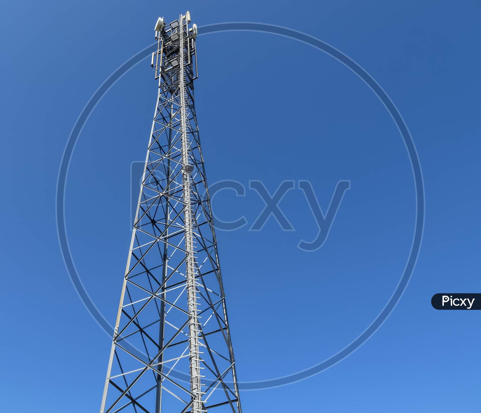 Electric Antenna And Communication Transmitter Tower In A Northern European Landscape Against A Blue Sky