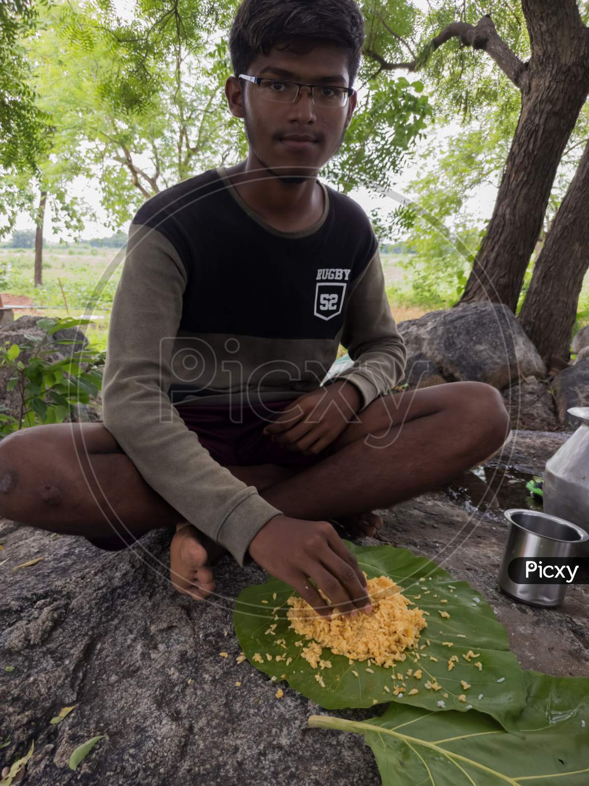 South Indian boy/teen eating food recipe with rice, dal and mango pickle.