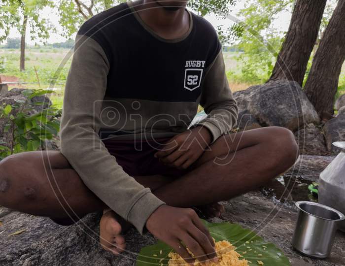 South Indian boy/teen eating food recipe with rice, dal and mango pickle.