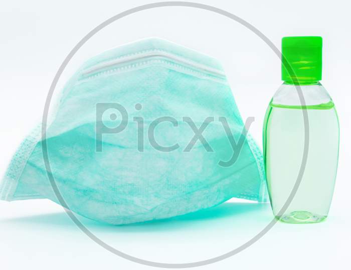 Surgical Face Mask And Bottle Of Hand Sanitizer Are Isolated On White Background