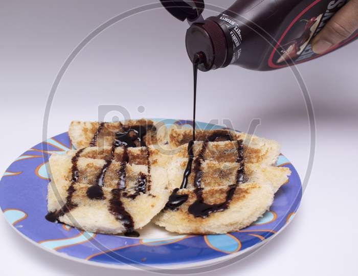 Decorating Hot Choco Lava Bread By Pouring And Garnishing With Chocolate Syrup Or Sauce