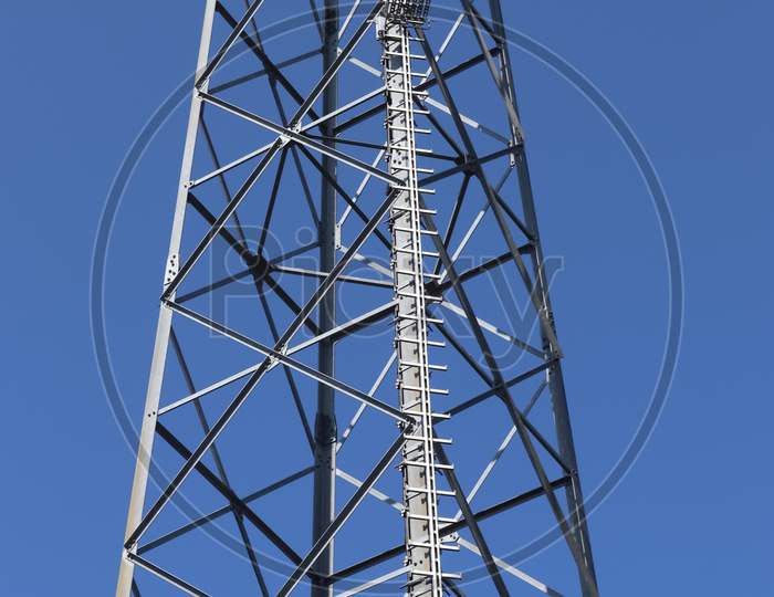 Electric Antenna And Communication Transmitter Tower In A Northern European Landscape Against A Blue Sky