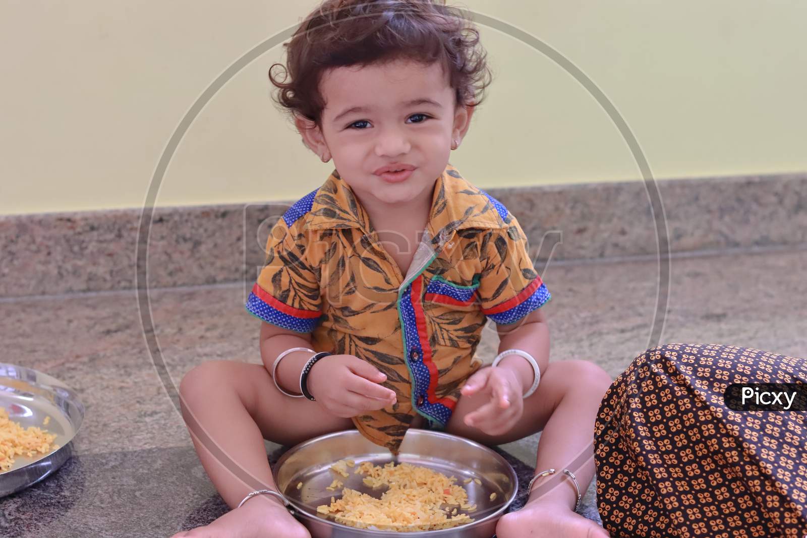 A Child Sits Inside The House Eating Food