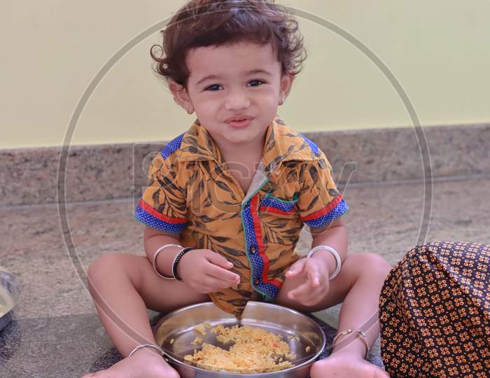 A Child Sits Inside The House Eating Food