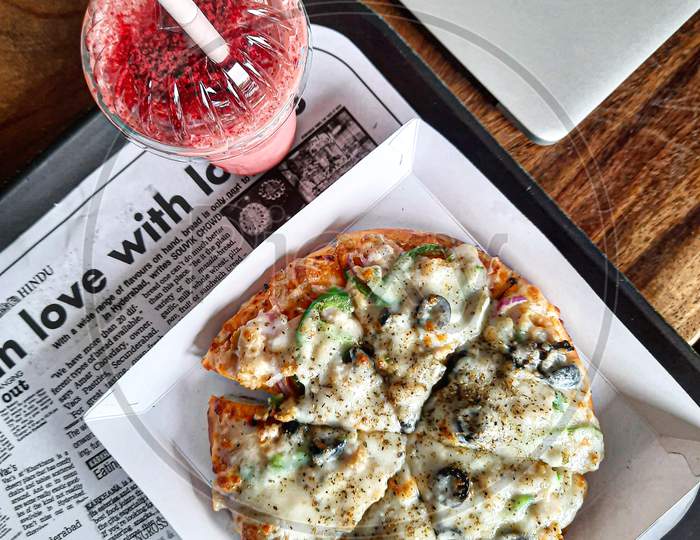 Pizza & Red velvet milkshake on a tray.