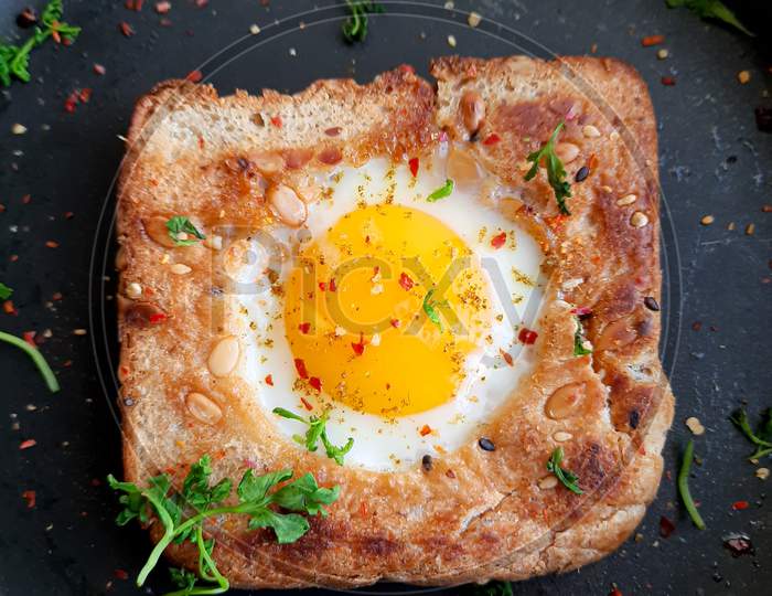 Egg in a hole topped with herbs, chilli flakes