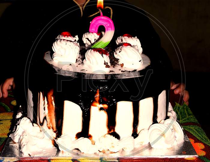 Birthday Drip Cake And Burning Candle With Chocolate And Sprinkles Isolated Black Background Banner With Party Decor. Celebration Concept. Trendy Drip Cake