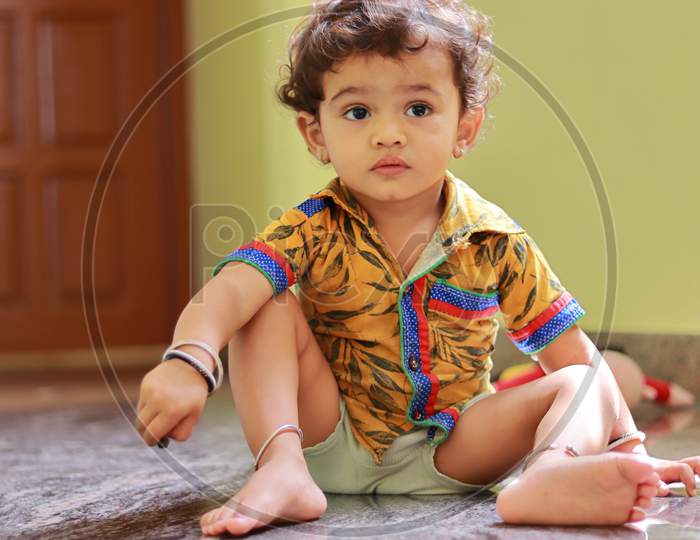 A Child Sitting On The Ground Inside The House