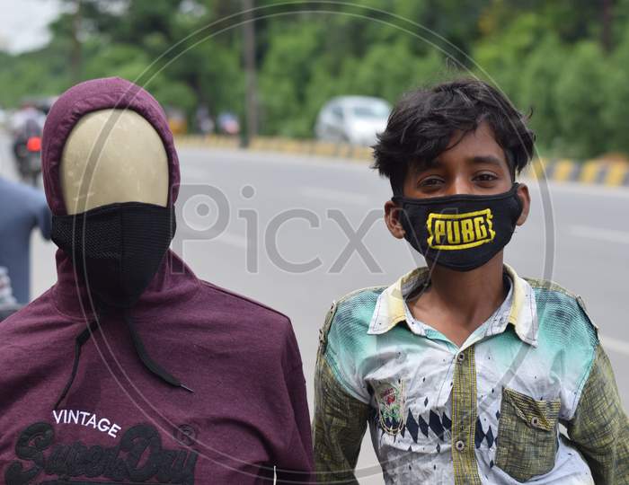 Hyderabad, Telangana, India. july-22-2020: wearing a mask to the doll, a boy standing next to the toy at road side, corona pandemic time