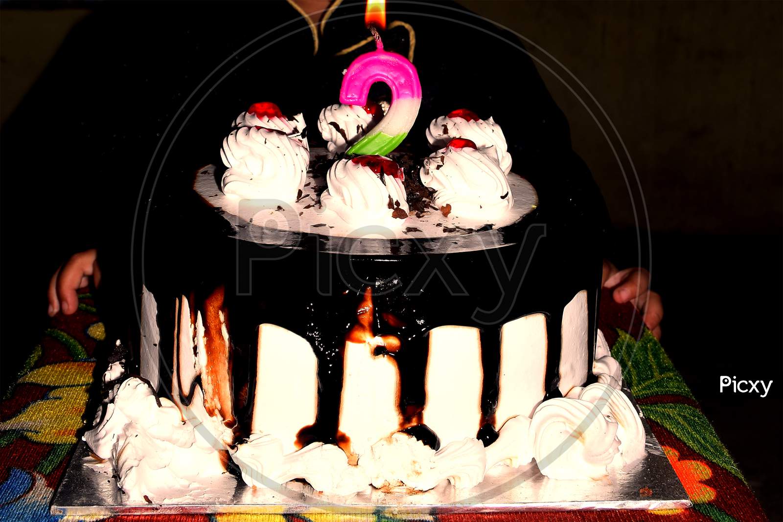 Birthday Drip Cake And Burning Candle With Chocolate And Sprinkles Isolated Black Background Banner With Party Decor. Celebration Concept. Trendy Drip Cake