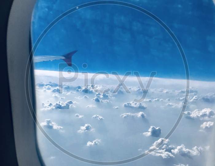 clicked through plane window , blue sky above clouds , clouds through window