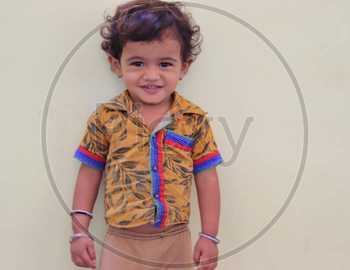 Cute Child Standing Near By White Wall