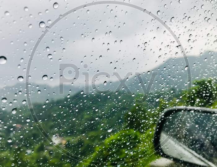 clicked through window , car window with rain drops , mountain view in rain , perfect click through car window