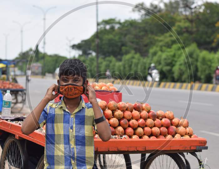 Hyderabad, Telangana, India. july-22-2020: sad news of corona virus, the child who needs to be educated is selling fruits, boy wearing protective face mask at road side, corona pandemic time